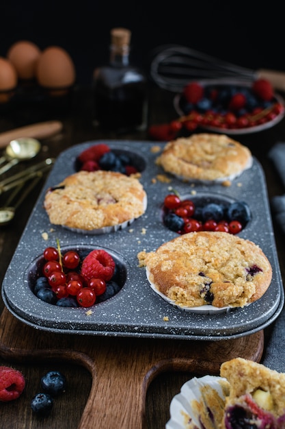 Muffins de Streusel com mirtilo, framboesa e groselha na mesa de madeira rústica