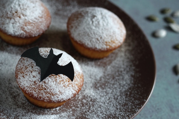 muffins em açúcar de confeiteiro com sementes de abóbora e morcego preto