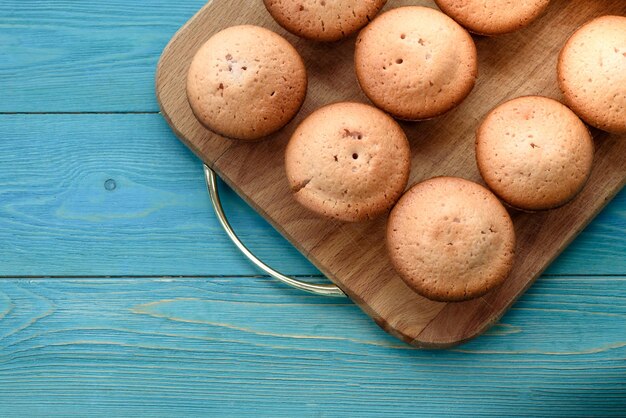 Muffins frescos en una tabla de cortar sobre un fondo azul de madera BackgroundxATexture de muffin recién horneado Closeup Macro