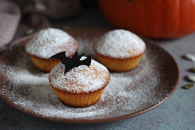 Muffins in Puderzucker mit Kürbiskernen und schwarzer Fledermaus