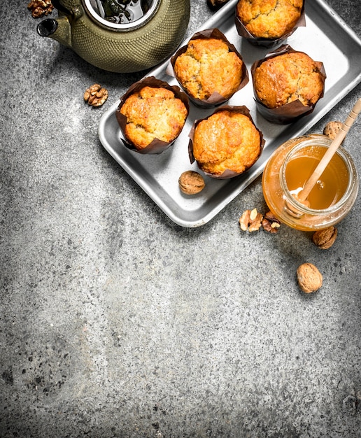 Muffins de miel con una tetera en la mesa rústica.