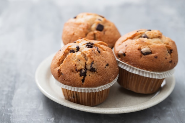 Muffins mit Schokolade auf weißem Teller auf Keramikhintergrund