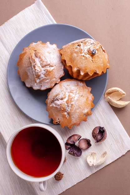 Muffins de nuez de pacana con una taza de té en un plato de fondo gris con cupcake