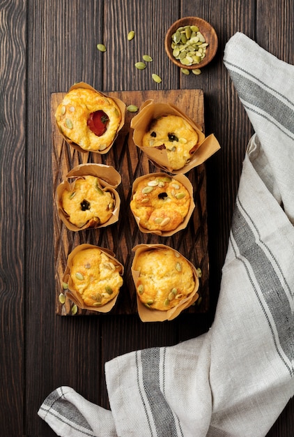 Muffins de queso saludable con polenta, tomate cherry y pipas de calabaza para el desayuno. Enfoque selectivo. Vista superior. Copie el espacio.