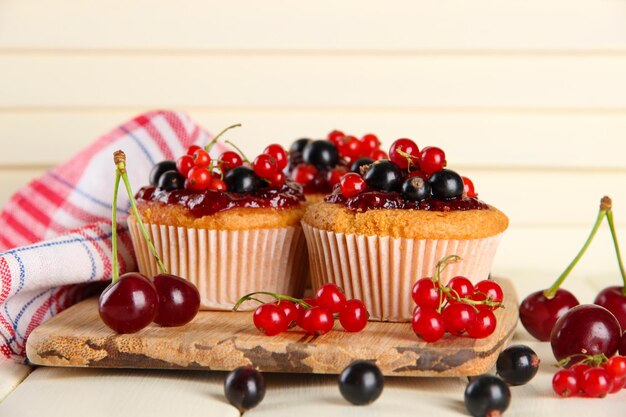 Foto muffins saborosos com bagas em uma mesa de madeira branca