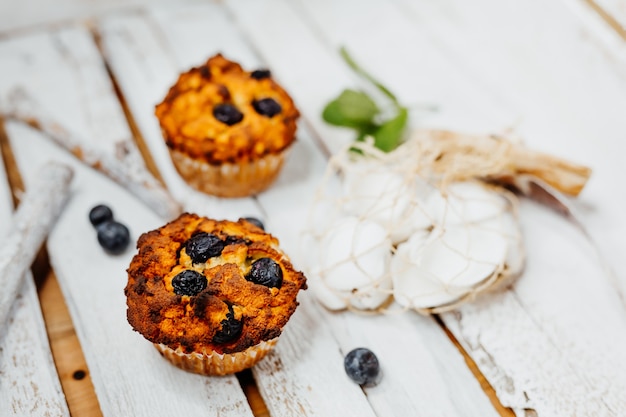 muffins saludables con harina de coco y arándanos en placa de madera clara decorada con menta