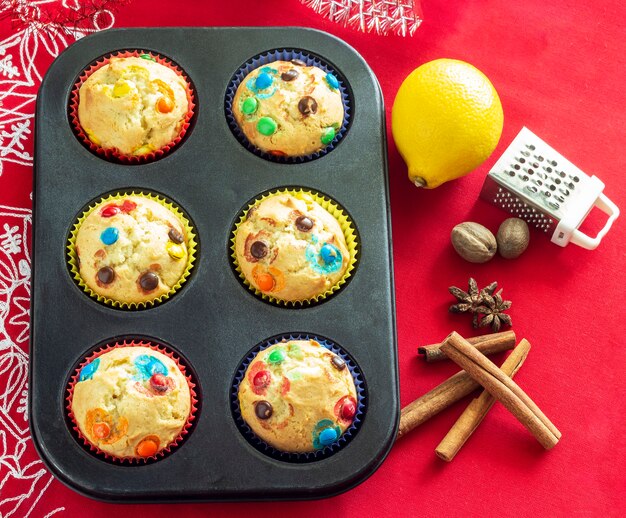 Muffins de vainilla con caramelo de chocolate, picante y limón. Concepto de panadería de Navidad. Vista superior. Fondo de arpillera roja. Copie el espacio.