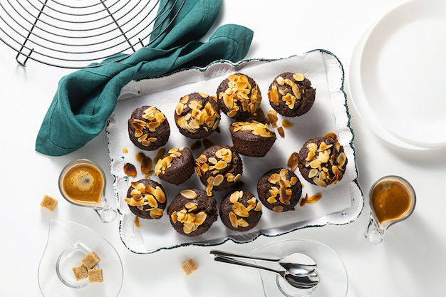 Muffins veganos com chips de banana e amêndoa com café expresso na bandeja.