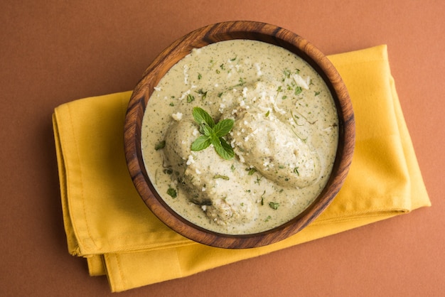 Mughlai o Haryanvi estilo Methi Malai Kofta en crema blanca, plato principal vegetariano indio popular servido en un tazón de madera con Chapati o Roti, enfoque selectivo