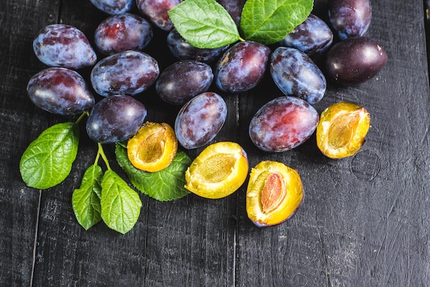 Muitas ameixas frescas em fundo preto. Copiar espaço