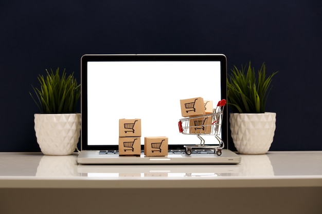 Muitas caixas de papel em um pequeno carrinho de compras em um teclado de laptop - conceitos sobre compras online que os consumidores podem comprar diretamente de sua casa ou escritório com apenas alguns cliques no navegador da web