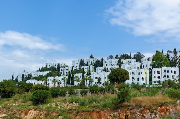 Muitas casas são cercadas por árvores verdes na encosta suave. a bela paisagem da cidade da turquia sobre o fundo azul do céu nublado.