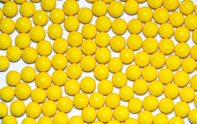 Muitas drageias redondas amarelas de vitamina C de ácido ascórbico isoladas em fundo branco