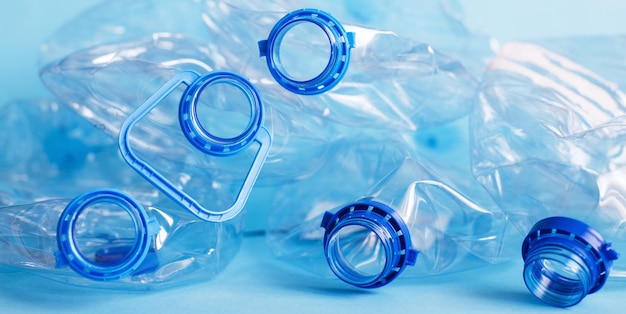 Muitas garrafas usadas amassadas vazias de plástico em um conceito de poluição e desperdício de fundo azul