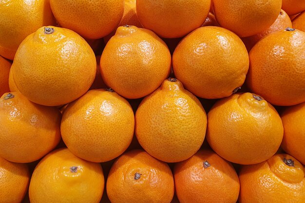 Muitas laranjas suculentas e brilhantes depositadas exatamente em uma pilha em uma loja no mercado