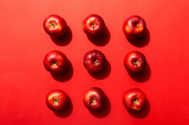 Muitas maçãs vermelhas na vista superior do fundo colorido padrão de outono com maçã fresca acima da vista