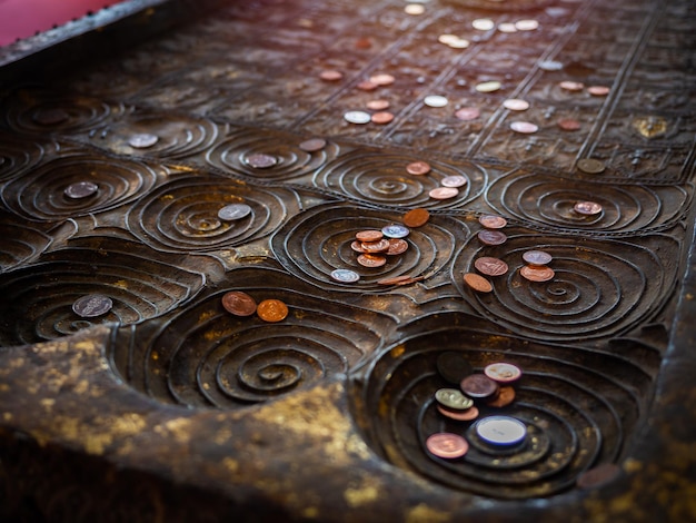 Muitas moedas colocadas na réplica da pegada de Buda no templo