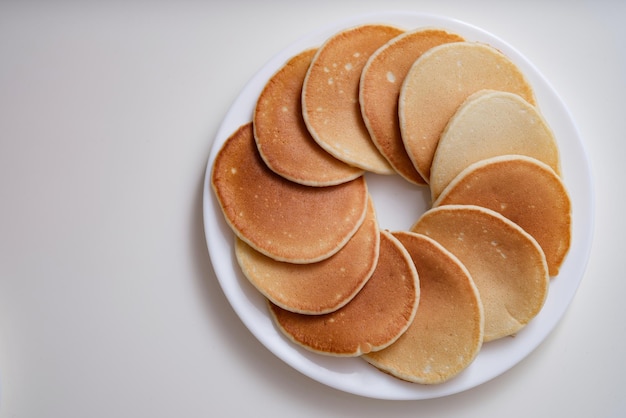 Muitas panquecas deliciosas e apetitosas em um prato branco com vista de topo do círculo