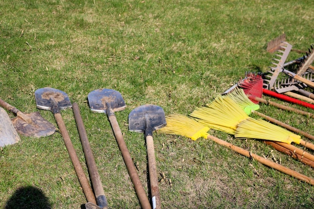 Muitas pás de ancinhos e escovas para limpar o território estão na grama verde