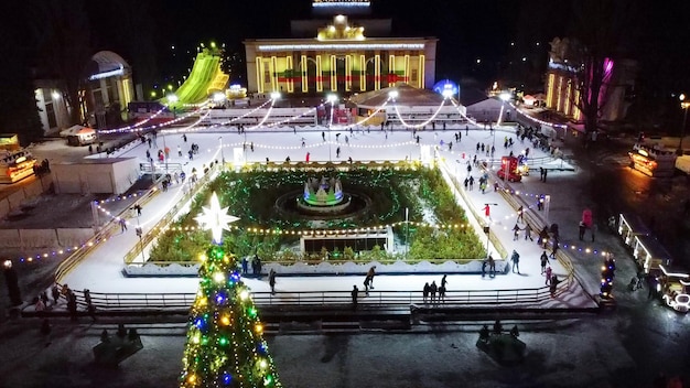 Muitas pessoas patinando na bela pista de patinação no gelo ao ar livre decorada ano novo natal iluminado