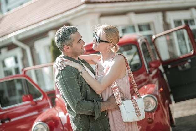 Muito amor. lindo casal se abraçando em frente ao carro-retrô aberto.