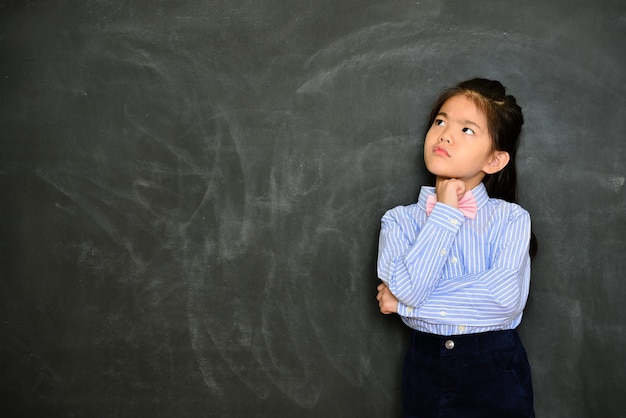 muito bonitinha professora pensando no planejamento de ensino da aula quando ela está na frente do quadro-negro. conceito de educação escolar.