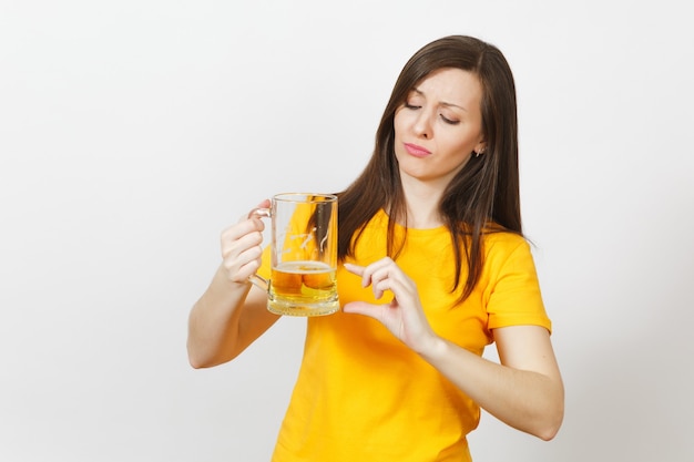 Muito europeia jovem triste chateada, fã de futebol ou jogador de uniforme amarelo segura a caneca de cerveja, se preocupa em perder o time isolado no fundo branco. esporte, jogue futebol, conceito de estilo de vida.