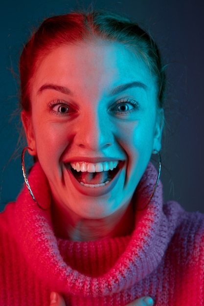 Muito feliz, close-up. Retrato da mulher caucasiana isolado no fundo do estúdio gradiente em luz de néon. Linda modelo feminino com cabelo ruivo. Conceito de emoções humanas, expressão facial, vendas, anúncio.