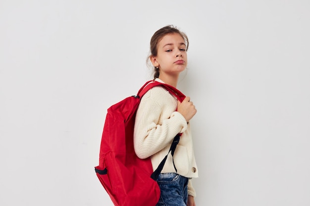 Muito jovem colegial com mochila vermelha posando de fundo isolado