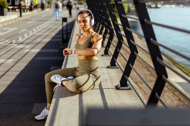 Muito jovem com fones de ouvido faz uma pausa depois de correr na área urbana