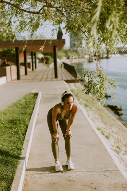 Muito jovem com fones de ouvido fazendo uma pausa durante o exercício fora