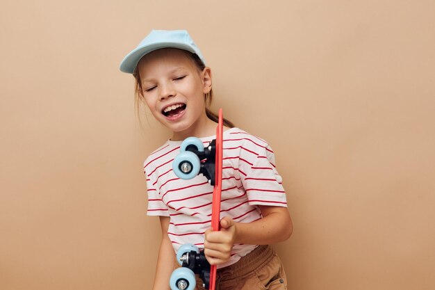 Muito jovem com um skate infantil na mão sorria fundo isolado