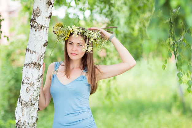 Muito jovem com uma coroa de flores na cabeça em uma floresta