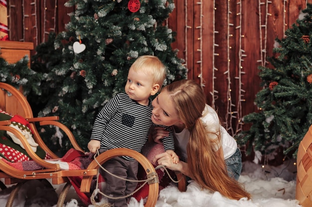 Muito jovem com uma criança de um ano brincando perto da árvore de Natal