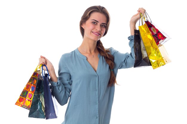 Muito jovem de blusa azul segurando sacolas de compras em fundo branco no estúdio