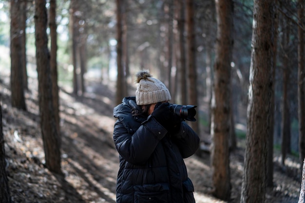 muito jovem em roupas quentes, andando por uma floresta tirando fotos