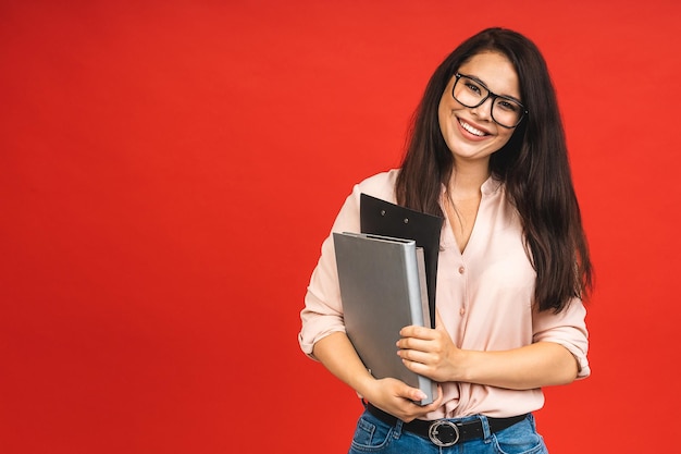 Muito jovem empresária em laptop segurando casual no escritório isolado sobre fundo vermelho