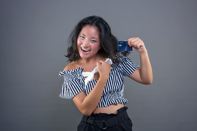 Muito jovem, feliz e sorridente, chinesa mostrando cartão de crédito