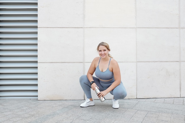 Muito jovem feliz em forma e tamanho grande descansando após o treino e bebendo água