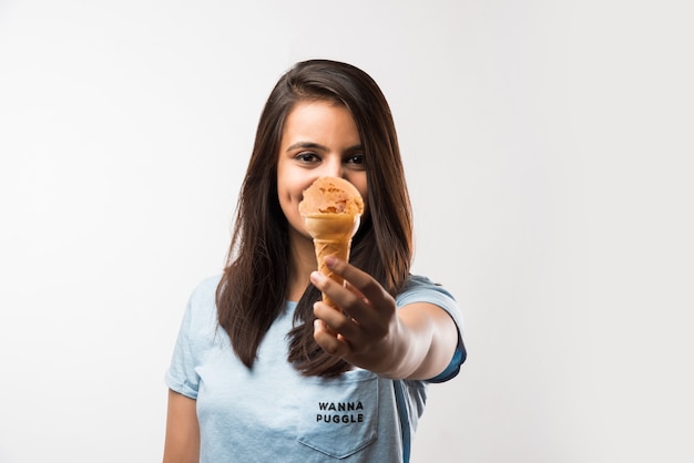 Muito jovem garota indiana asiática comendo ou apresentando sorvete em cones, isolada sobre um fundo branco