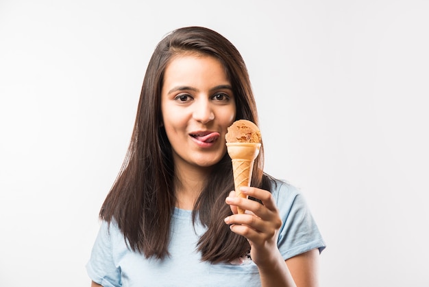 Muito jovem garota indiana asiática comendo ou apresentando sorvete em cones, isolada sobre um fundo branco