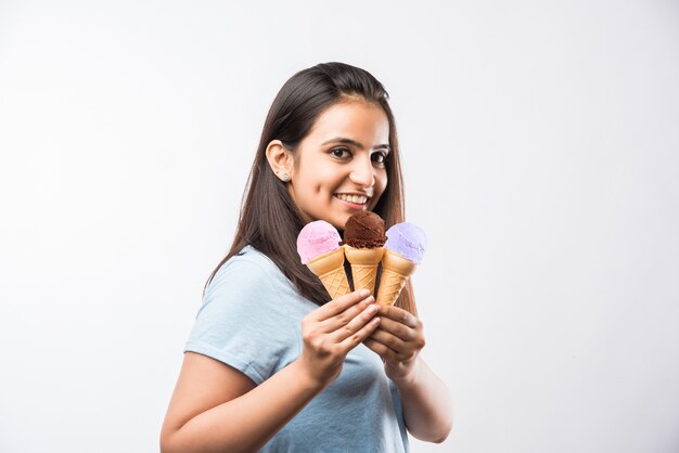 Muito jovem garota indiana asiática comendo ou apresentando sorvete em cones, isolada sobre um fundo branco