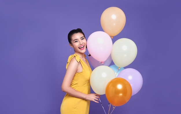 Muito jovem mulher asiática na festa de celebração, segurando um balão colorido e rosto de sorriso. Feliz ano novo ou conceito de comemoração da véspera de aniversário.