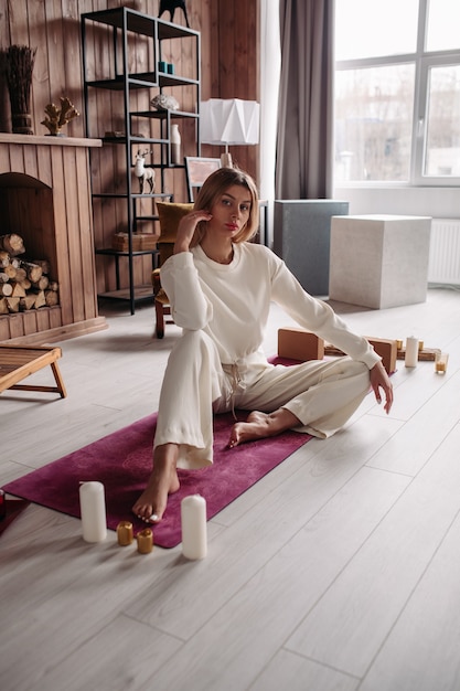 Muito jovem mulher calma meditando e relaxando sentado no tapete natural no interior aconchegante de casa no fim de semana. Bem-estar da mulher