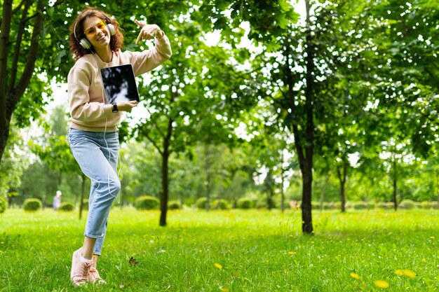 Muito jovem mulher caucasiana está envolvida em freelance no parque com o laptop