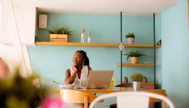 Muito jovem negra bebendo café enquanto trabalhava no laptop no café