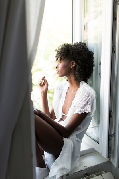 Muito jovem negra sentada na janela