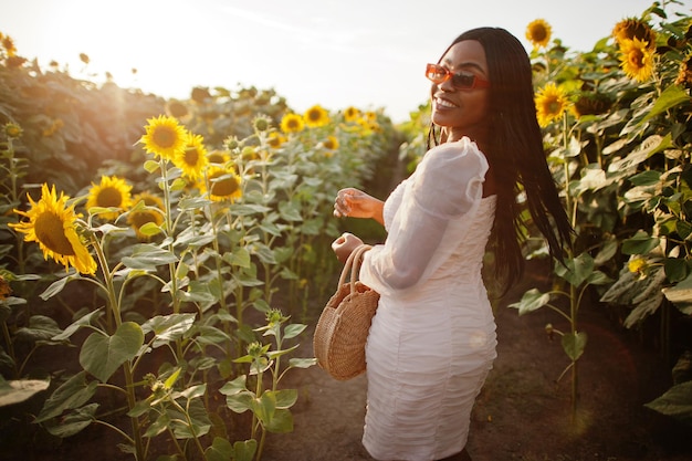 Muito jovem negra usa pose de vestido de verão em um campo de girassol.