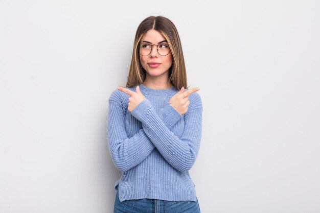 Muito jovem olhando confusa e confusa, insegura e apontando em direções opostas com dúvidas