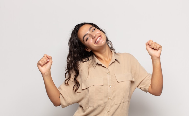 Foto muito jovem parecendo extremamente feliz e surpresa, comemorando o sucesso, gritando e pulando